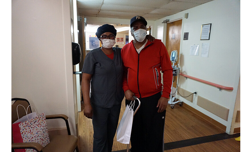 Extended Care Adopt-a-Resident Day 5-11-2022 Female employee giving gift bag to man in red for web