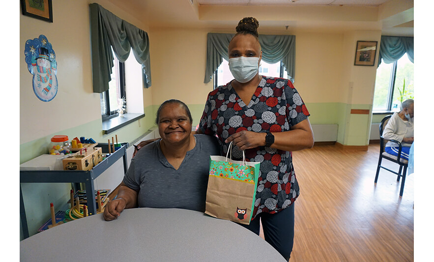 Extended Care Adopt-a-Resident Day 5-11-2022 Woman getting gift bag with owl from employee for web