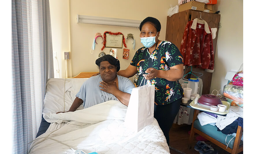 Extended Care Adopt-a-Resident Day 5-11-2022 Woman getting gift in room from employee for web