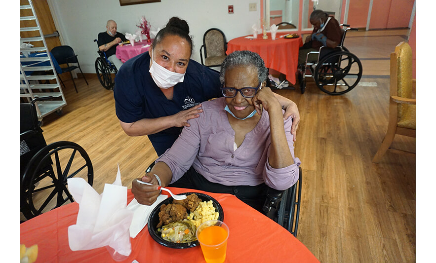 Extended Care Adopt-a-Resident Day 5-15-2024 Staff in blue scrubs with woman in purple for web