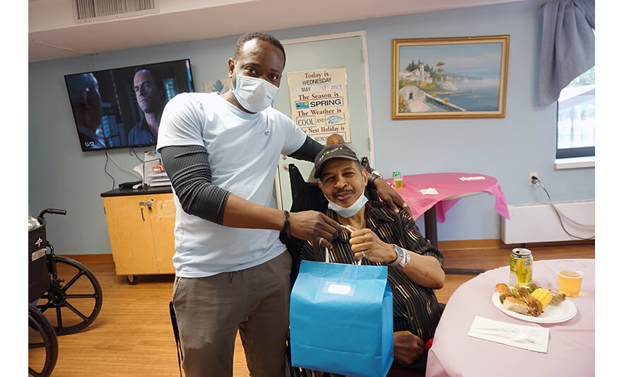 Extended Care Adopt-A-Resident Day 5-17-2023 Giving blue bag to man for web