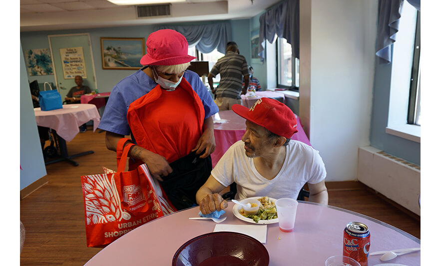 Extended Care Adopt-A-Resident Day 5-17-2023 Giving shirt and shorts to man in red hat for web