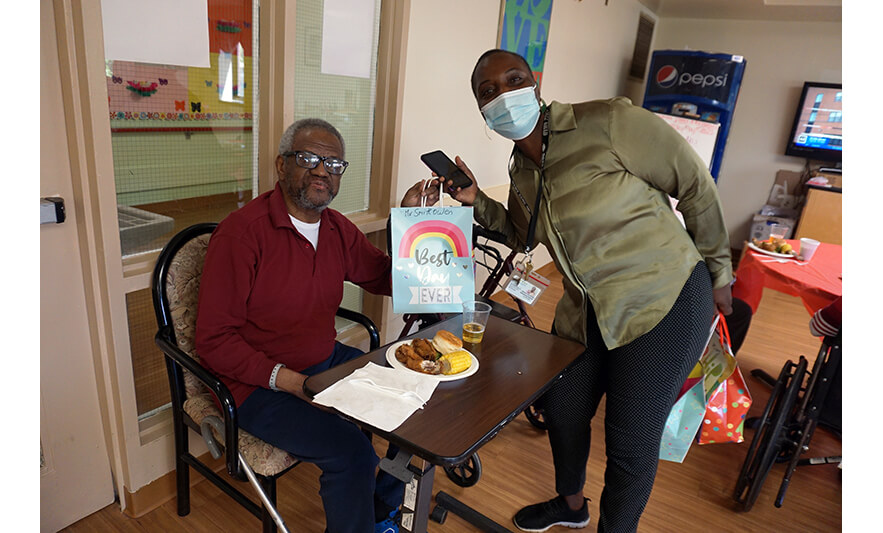 Extended Care Adopt-A-Resident Day 5-17-2023 Julienne Van-Nooten giving bag to man for web