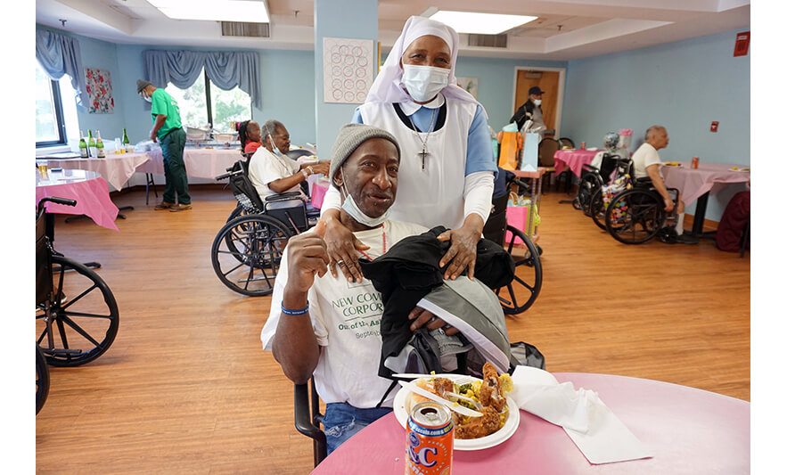 Extended Care Adopt-A-Resident Day 5-17-2023 Sister Elizabeth Lima giving clothes to man for web